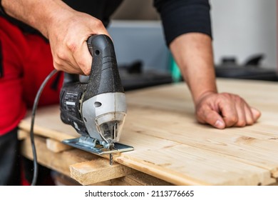 Close up on hand of unknown carpenter working with an electric jigsaw cutting wood with saw woodworking hobby concept copy space - Powered by Shutterstock