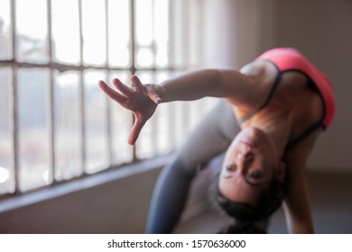 Close Up Of On Hand Of Young Athletic Woman Doing Wild Thing Yoga Pose In Urban Space By Large Window Reaching Toward Camera. Caucasian Woman In Her 20s Practicing Camatkarasana