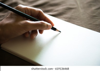 close up on the hands of an artist drawing a pencil sketch , hand holds a pencil and draws