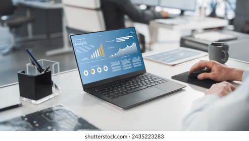 Close Up On Hands of Caucasian Male Professional Working in a Business Research and Development Company. Manager Analyzing Financial Reports, Looking at a Laptop Computer Screen with Graphs and Charts - Powered by Shutterstock