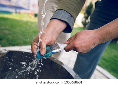 Close up on hands of a craftsman washing a brush cleaning after the painting work finished job - Powered by Shutterstock