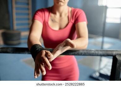 Close up on hands of female gymnast in pink sportswear rubbing hands dusted in chalk after practicing bar routines in gym, copy space - Powered by Shutterstock