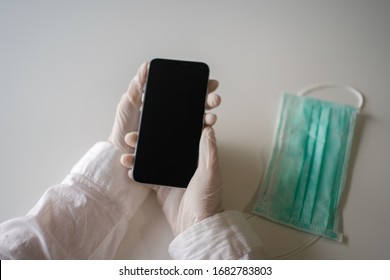 Close Up On Hands In Medical Gloves Using Mobile Smartphone. Protective Care Mask. Emergency Problem. Healthcare Employee, Distance Working Learning Concept. Modern Mobile Smartphone Background
