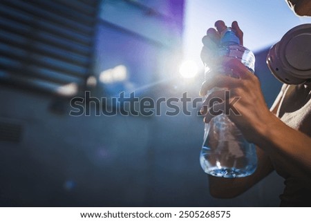 close up on hands midsection of unknown caucasian woman open plastic bottle of water while stand outdoor in sunny day