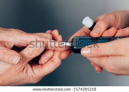 close up on the hands of a nursery testing the glucose values in a female diabetic patient - control of hypoglycemia new medical devices concept