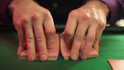 Close Up On Hands Of Professional Poker Dealer Doing A Riffle Shuffle Of Playing Cards Before High Stakes Game In Luxurious Casino. Anonymous Croupier Shuffling Deck Before Tournament