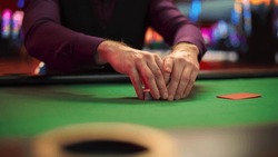 Close Up On Hands Of Professional Poker Dealer Doing A Riffle Shuffle Of Playing Cards Before High Stakes Game In Luxurious Casino. Anonymous Croupier Shuffling Deck Before Competitive Tournament.
