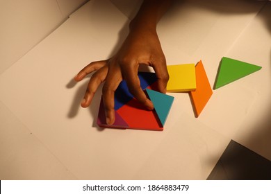 Close up on hands of small Child solving Tangram puzzle white background