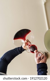 Close Up On Hands Of Unknown Caucasian Man Pouring Red Wine From Bottle In The Decanter At Home In Day - Low Angle View Copy Space