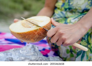 Close up on hands of unknown caucasian woman cutting melon in summer day with knife on the field prepare fresh organic raw food on picnic - Powered by Shutterstock