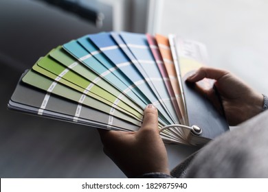 Close up on hands of unknown female person holding color palette at home in apartment - Woman choosing paint material for house renovation - decoration and innovation concept - Powered by Shutterstock