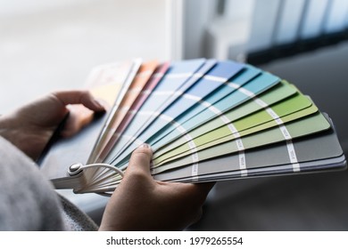 Close up on hands of unknown female person holding color palette at home in apartment - Woman choosing paint material for house renovation - decoration and innovation concept