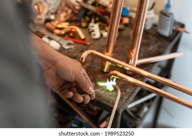 Close up on hands of unknown industrial worker plumber with central heating copper pipes welding using gas torch or blowtorch at work