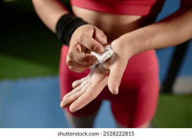 Close up on hands of unrecognizable female gymnast rubbing chalk into palms applying magnesia powder for stronger grip on high bar in gym, copy space - Powered by Shutterstock