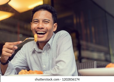 Close Up On Handsome Asian Man Using Fork With Nugget And Try To Eating Piece Of Fried Chicken At Outdoor Restaurant On Weekend Day With Chill Time, Happy Lifestyle Concept