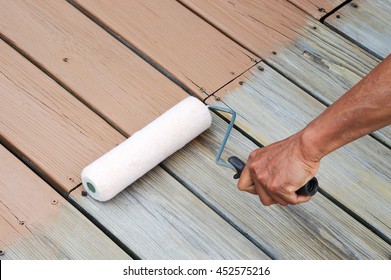 Close Up On Handyman Painting The Old Deck With Roller