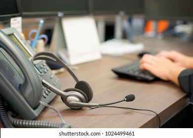 Close Up On Headset Of Call Center Leaning On Telephone With Blur Network Engineering Typing On Keyboard For Reply Case To Customer Or Monitoring Alarm , Technology Concept