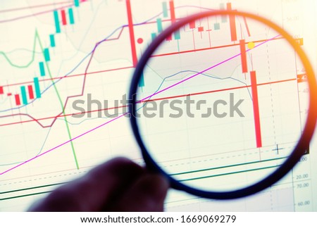 Close up on Japanese stock market candles showing a large drop magnified with a magnifying glass