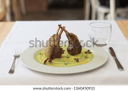 Close up on lamb ribs served on a green vegetables purea, background is  defocused restaurant. Foto d'archivio © 