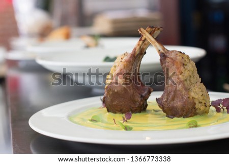 Close up on lamb ribs served on a green vegetables purea, background is  defocused restaurant. Foto d'archivio © 