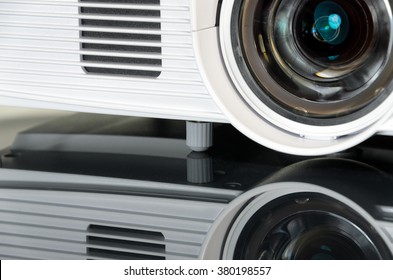 Close Up On The Lens Of A White Home Cinema Projector, Mirroring On The Surface.