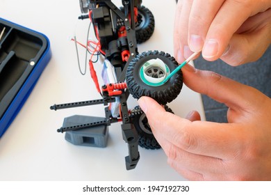 Close Up On A Male Hands While Painting Rims Of A Scale Model Machine. Scale Model Passion Concept. Repair, Care And Cleaning Of A Scale Model Car. Man During A Restyling Of Vehicle's Wheels.