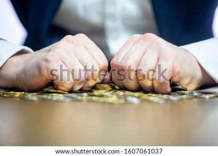 Close up on male's hands holding tightly the coins. Greed concept.