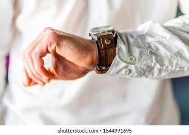 Close up on man checking his wrist watch time clock midsection wearing white shirt