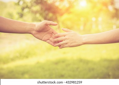 Close up on a man and a woman holding hands at green background,Hand help and hope concept,helping hand green background. - Shutterstock ID 432981259