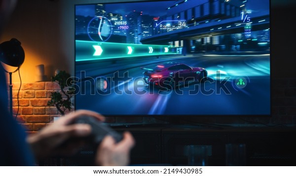 Close\
Up on Man\'s Hands at Home, Sitting on a Couch in Stylish Loft\
Apartment and Playing Arcade Car Video Games on Console. Male Using\
Controller to Play Street Racing Drift\
Simulator.