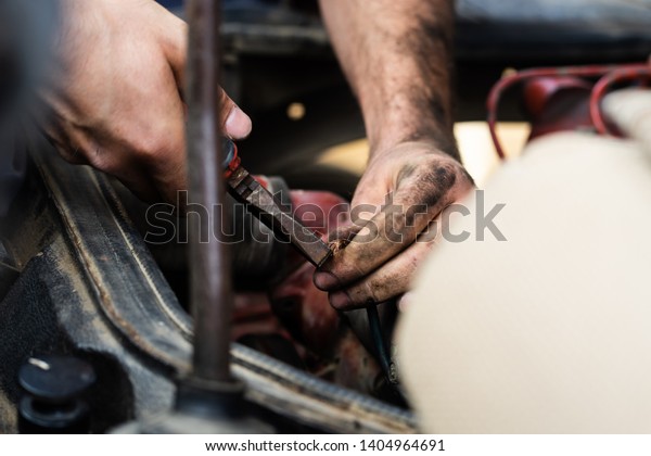 Close up on mechanic repair man electrician using\
hand tool combined pliers to connect copper wires on the motor\
engine block of the truck
