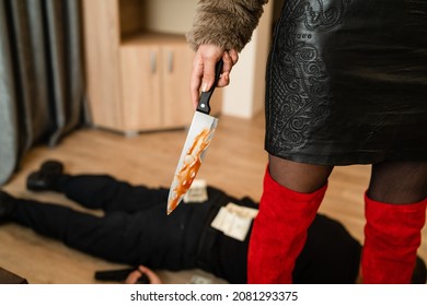 Close up on midsection of unknown woman female murderer holding bloody knife with unknown man lying dead on the floor stabbed with money banknotes around domestic violence human trafficking concept