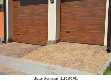 Close Up On Modern House Two Garage Doors Entrace With Rain Gutter Pipes And Pavement. 