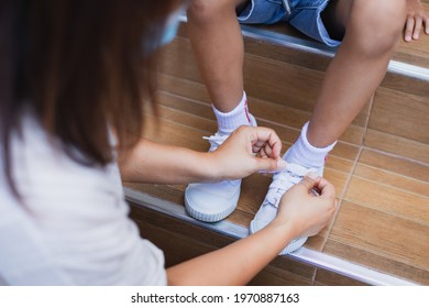 Close up on mother hand tie the child shoe. Mother helping her daughter tying the shoelace before go outside. - Powered by Shutterstock