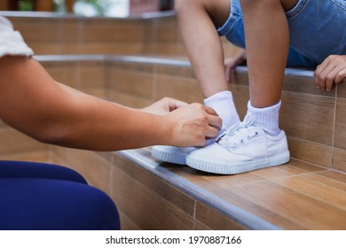 Close up on mother hand tie the child shoe. Mother helping her daughter tying the shoelace before go outside. - Powered by Shutterstock