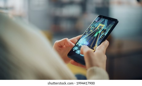 Close Up On A Person Hands Playing An Arcade Video Game On A Vertically Held Smartphone At Home Living Room. Feminine Hands Tapping The Mobile Phone Screen With A Colorful Game Over The Internet.