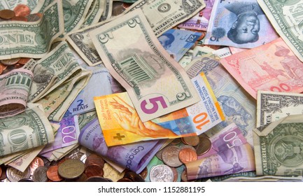 Close Up On Pile Of Many Bank Notes From Various Countries From Around The World. U.S., German, Swiss, Canadian, Brazilian, Vietnamese, Mexican. Many Countries Represented In Currency. Bills And Coins