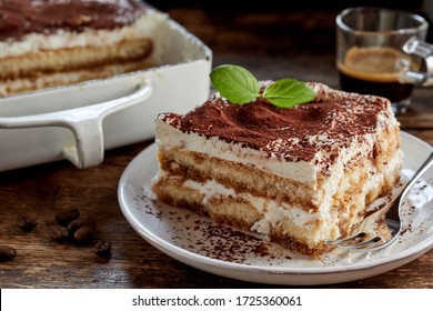 Close up on a portion of gourmet tiramisu Italian dessert topped with a sprig of mint served on a plate at table in a side view - Shutterstock ID 1725360061