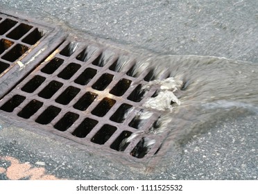 Close Up On Rain Water Flowing Into Manhole On The Street