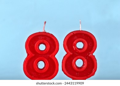 close up on a red number eighty eighth birthday candle on a white background.
