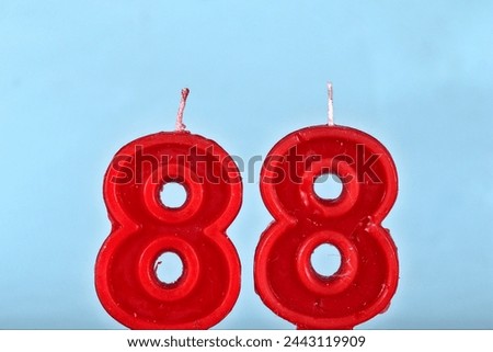 close up on a red number eighty eighth birthday candle on a white background.
