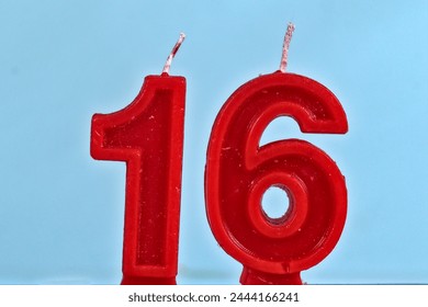 close up on red number sixteenth birthday candle on a white background.
