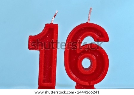 close up on red number sixteenth birthday candle on a white background.
