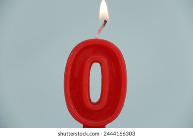 close up on a red number zero birthday candle with fire on a white background.
