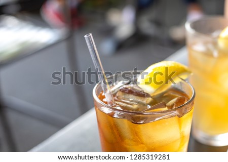 Close up on a reusable acrylic drinking straw, in a glass of ice tea