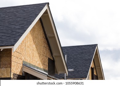 Close up on the roof of a residential house under construction, with plywood exterior siding and cloudy sky background