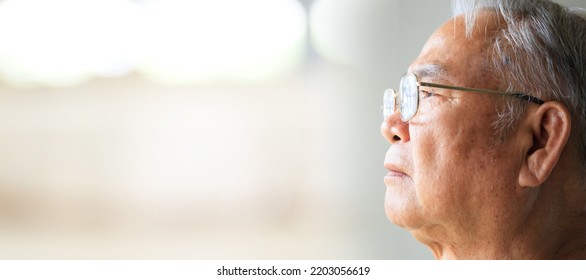 Close up on senior Asian elder man living lonely and looking outside the window. - Shutterstock ID 2203056619