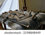 A close up on a set of items put on a boar or wolf hide, including some weapons, axes, swords, a coffer for jewelry, accesories, and smithing items seen next to a cloth tent in Poland