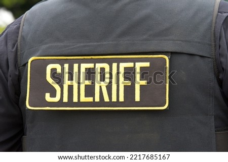 Close up on Sheriff letters on back of flack jacket.