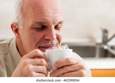 Close Up On Single Handsome Bearded Mature Man With Eyes Closed And Pleased Expression Sipping Coffee From Little White Tea Cup